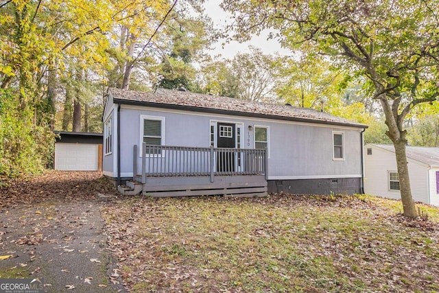 view of front of house featuring a garage, an outbuilding, and a deck