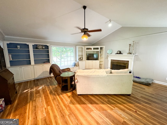 living room with hardwood / wood-style flooring, ornamental molding, ceiling fan, a fireplace, and lofted ceiling