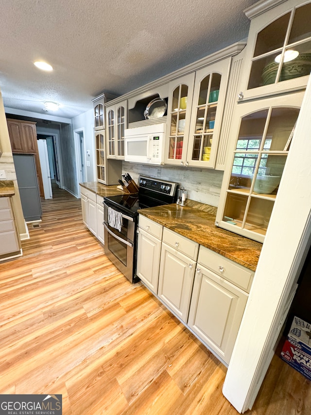 kitchen featuring white cabinetry, dark stone counters, a textured ceiling, light hardwood / wood-style flooring, and electric stove