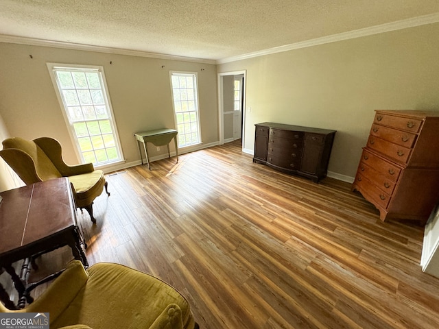 living area with ornamental molding, wood-type flooring, and a textured ceiling