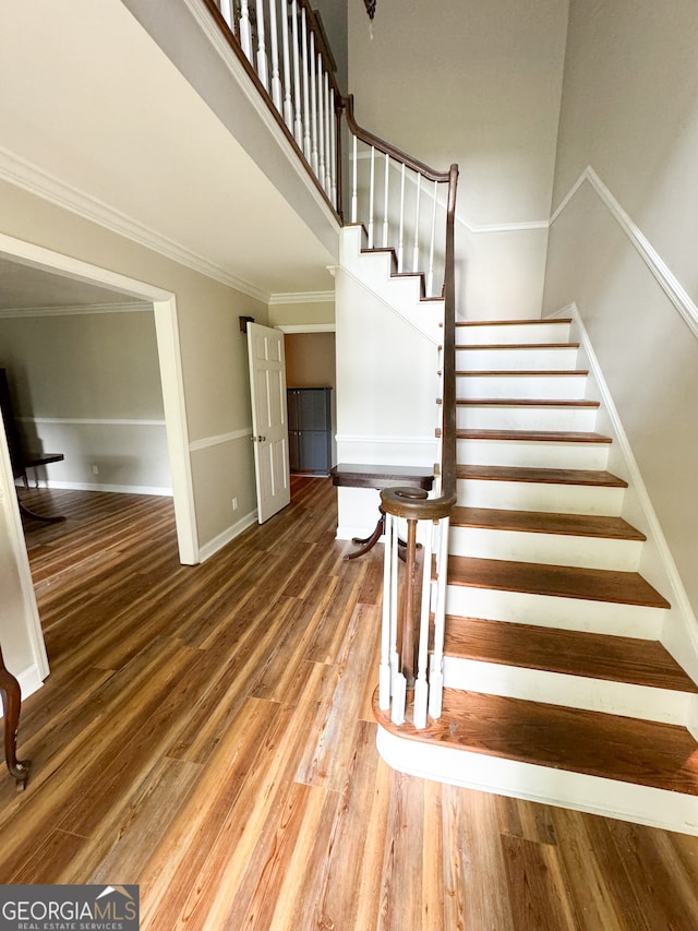 stairway with ornamental molding and hardwood / wood-style flooring