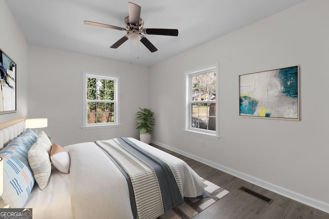 bedroom with multiple windows, ceiling fan, and dark hardwood / wood-style floors