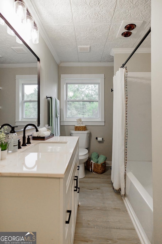 full bathroom with wood-type flooring, toilet, vanity, and a healthy amount of sunlight