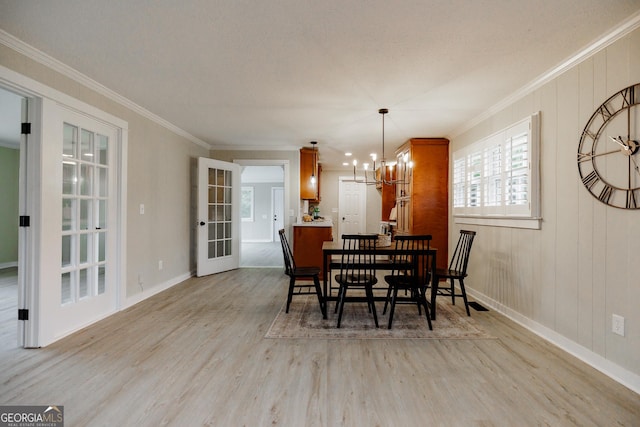 dining room with an inviting chandelier, ornamental molding, and light hardwood / wood-style flooring