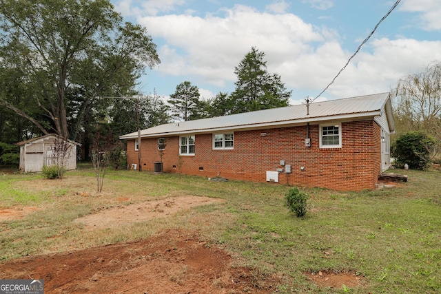 back of house with a storage shed, cooling unit, and a lawn