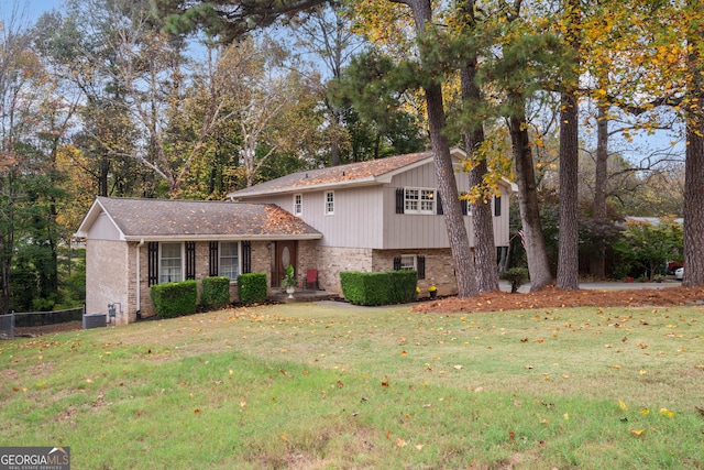 tri-level home featuring cooling unit and a front lawn