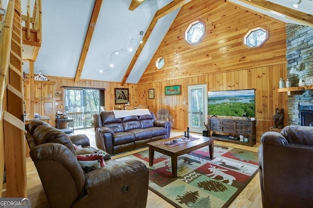 living room with a stone fireplace, wood-type flooring, wood walls, high vaulted ceiling, and beamed ceiling