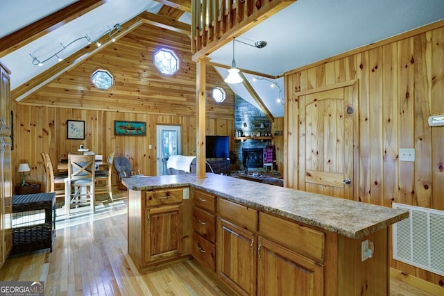 kitchen featuring light wood-type flooring, wood walls, vaulted ceiling with beams, and a kitchen island