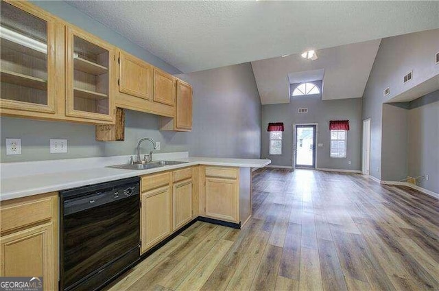 kitchen featuring lofted ceiling, black dishwasher, sink, light brown cabinets, and light wood-type flooring