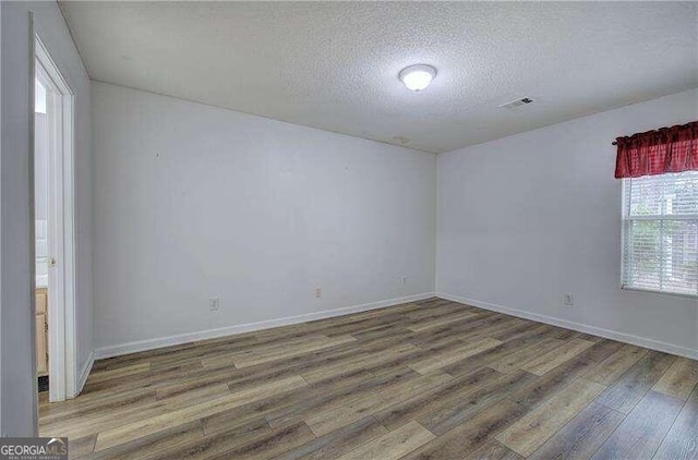 empty room with a textured ceiling and dark hardwood / wood-style floors