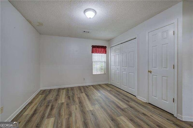 unfurnished bedroom featuring a textured ceiling and dark hardwood / wood-style floors