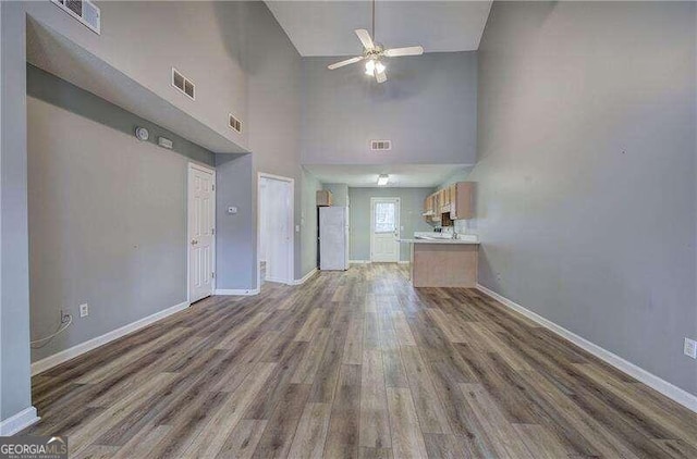 unfurnished living room featuring high vaulted ceiling, dark hardwood / wood-style flooring, and ceiling fan