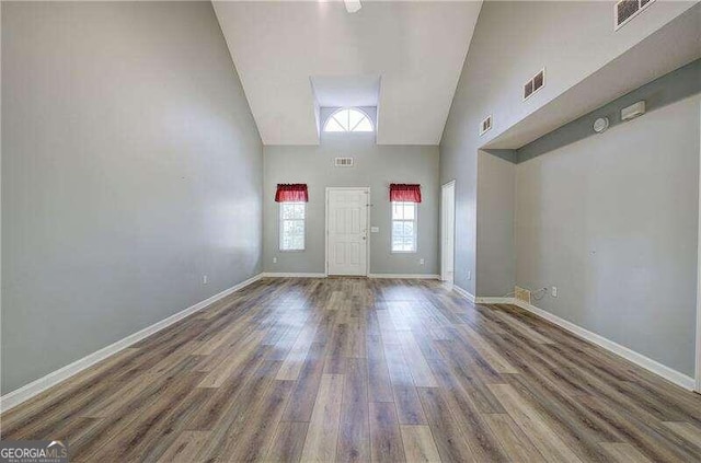 empty room with dark wood-type flooring and high vaulted ceiling