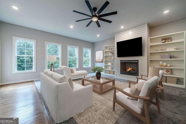 living room with a brick fireplace, light hardwood / wood-style floors, and ceiling fan