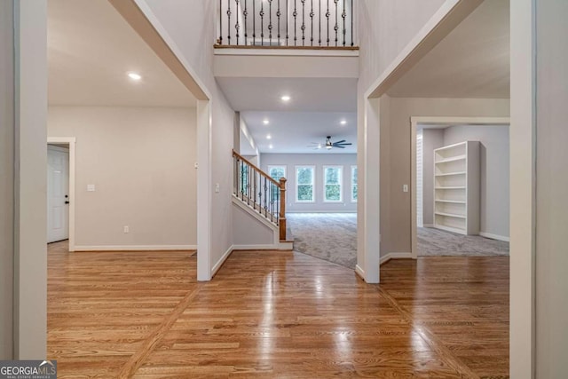 entrance foyer featuring a towering ceiling, ceiling fan, and light hardwood / wood-style flooring