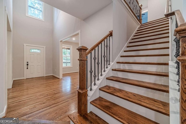 foyer with light hardwood / wood-style floors and a towering ceiling