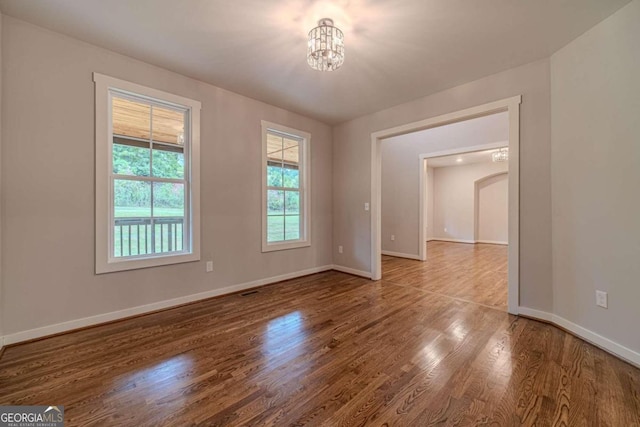 empty room with an inviting chandelier and hardwood / wood-style flooring