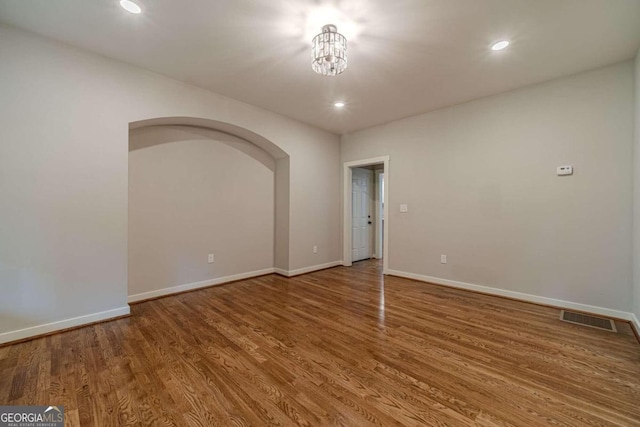 spare room with wood-type flooring and a chandelier