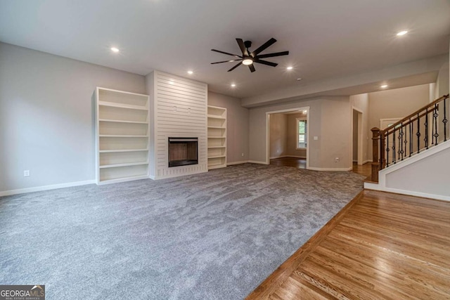 unfurnished living room featuring a fireplace, hardwood / wood-style flooring, ceiling fan, and built in features