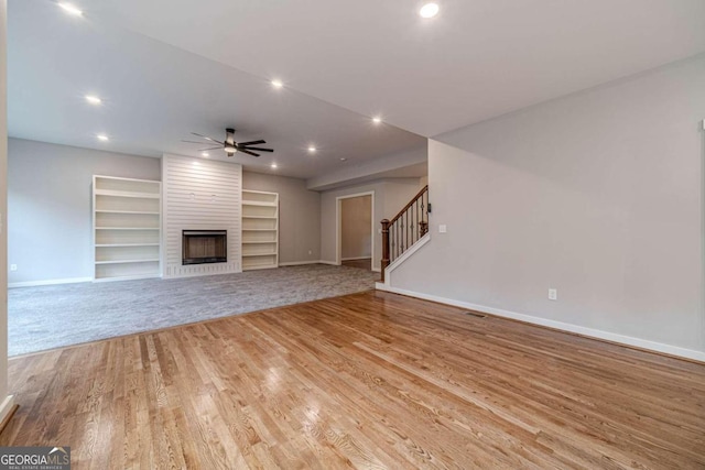 unfurnished living room featuring light wood-type flooring, a fireplace, ceiling fan, and built in features