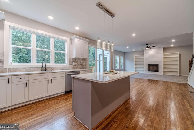 kitchen featuring white cabinetry, sink, decorative light fixtures, a kitchen island, and dishwasher