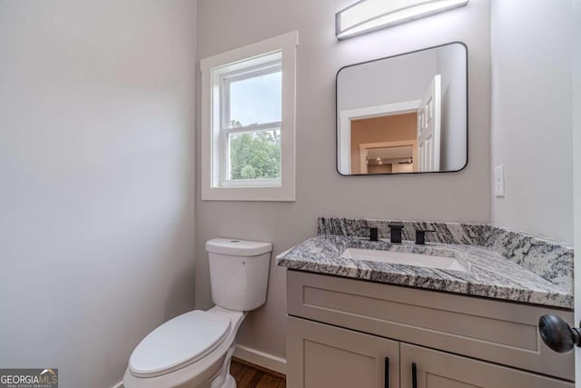 bathroom with hardwood / wood-style flooring, vanity, and toilet