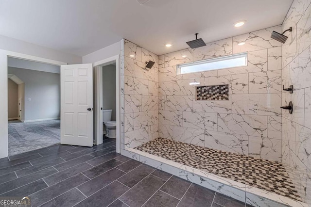 bathroom with toilet and a tile shower