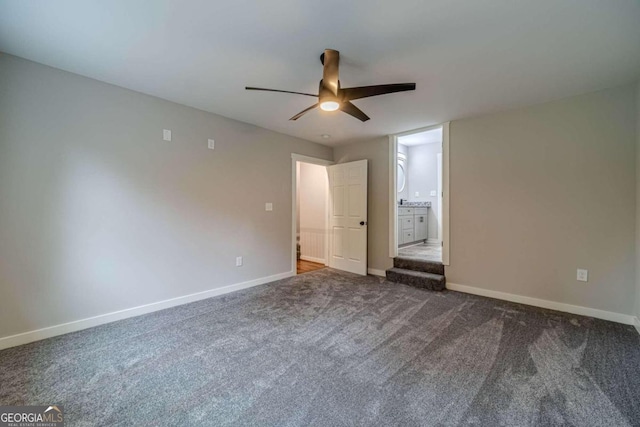 unfurnished bedroom featuring ensuite bath, ceiling fan, and dark colored carpet