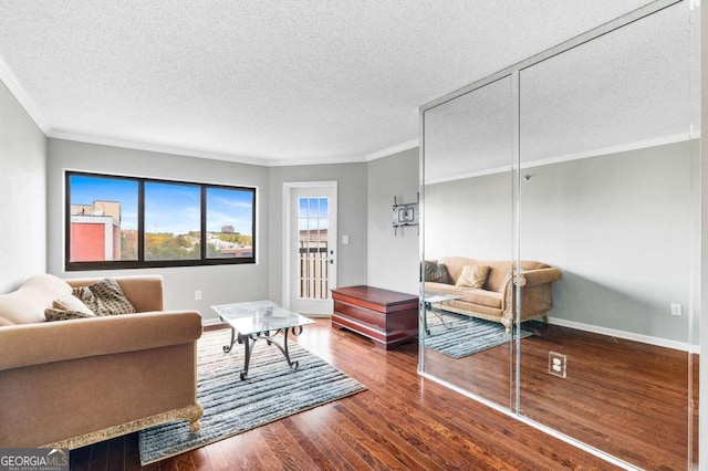 living room with hardwood / wood-style floors, ornamental molding, and a textured ceiling