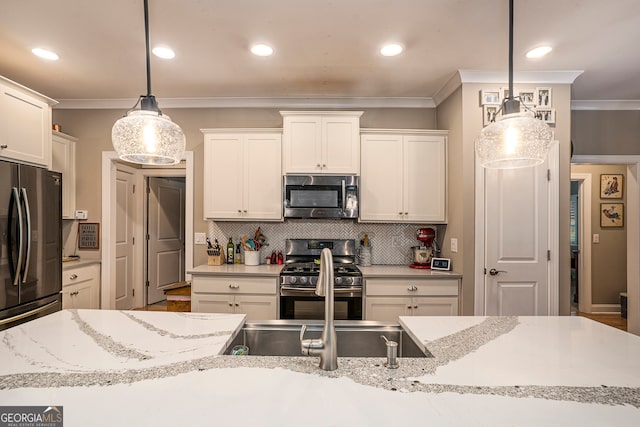 kitchen featuring stainless steel appliances, hanging light fixtures, white cabinetry, and ornamental molding