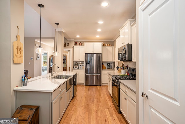 kitchen featuring sink, appliances with stainless steel finishes, hanging light fixtures, light hardwood / wood-style flooring, and white cabinets