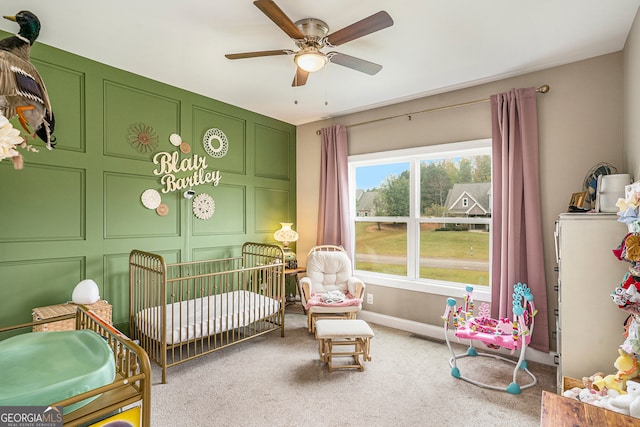 bedroom featuring a crib, ceiling fan, and carpet flooring