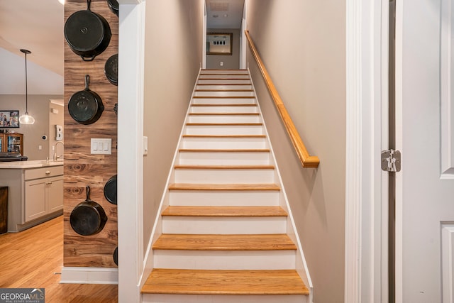 staircase featuring sink and hardwood / wood-style floors