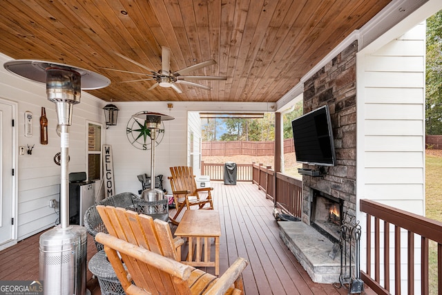 wooden terrace with ceiling fan and an outdoor stone fireplace