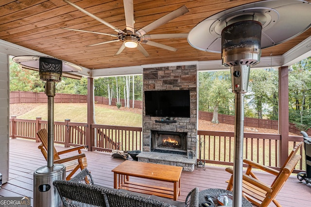 wooden deck with ceiling fan, a yard, and an outdoor stone fireplace