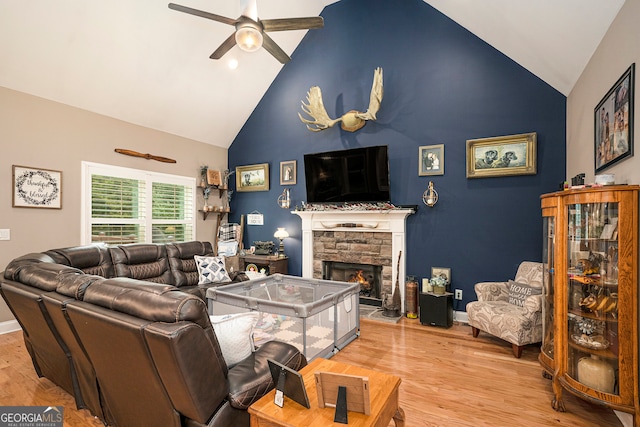 living room with a fireplace, light hardwood / wood-style floors, ceiling fan, and high vaulted ceiling