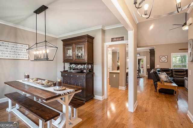 dining area featuring ornamental molding, light wood-type flooring, and ceiling fan with notable chandelier