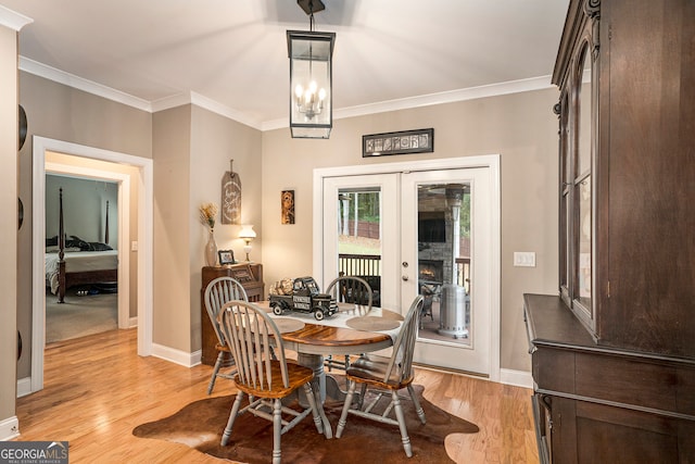 dining space with light hardwood / wood-style floors, crown molding, an inviting chandelier, and french doors