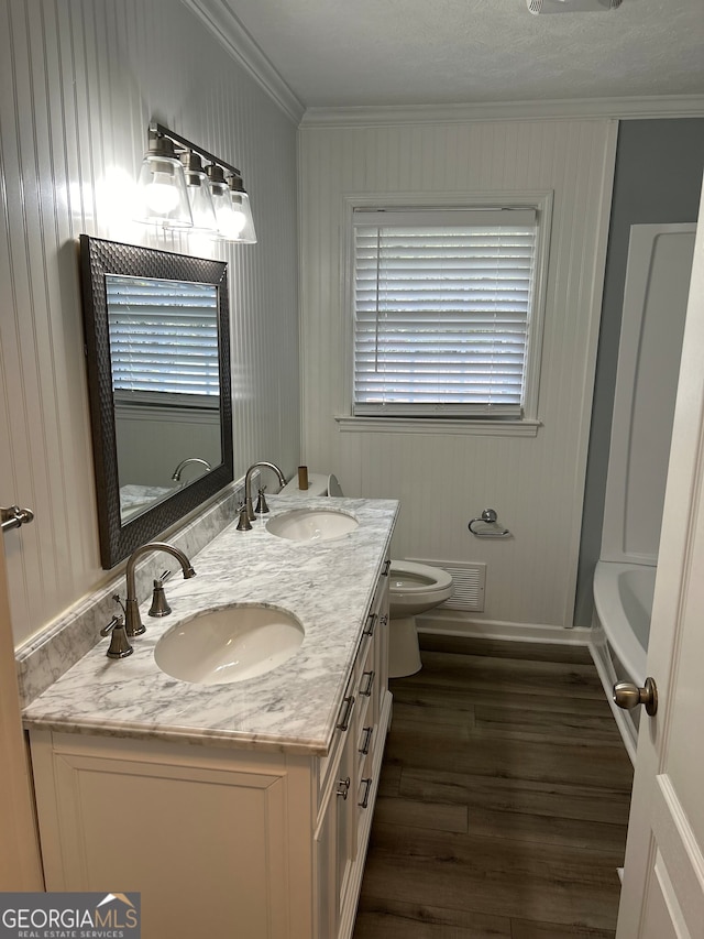 bathroom with hardwood / wood-style flooring, vanity, toilet, and crown molding