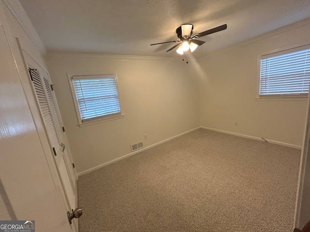 unfurnished bedroom featuring a closet, carpet flooring, ceiling fan, and crown molding