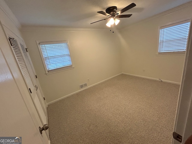 unfurnished bedroom featuring ornamental molding, a closet, light carpet, and ceiling fan