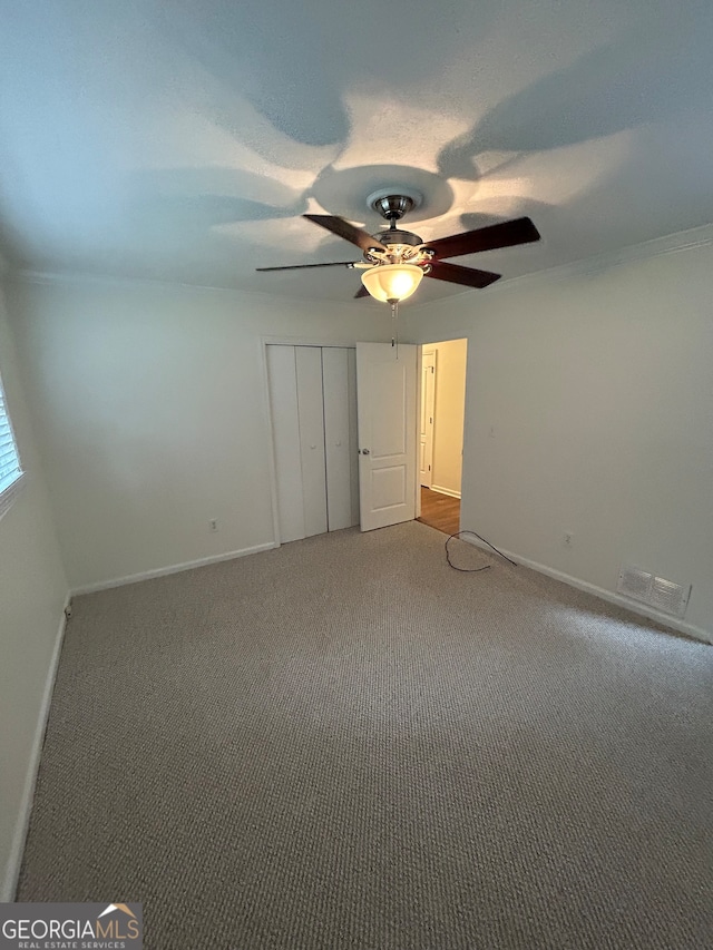 unfurnished bedroom featuring a closet, carpet flooring, and ceiling fan