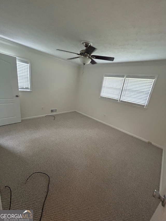 carpeted spare room featuring ceiling fan and plenty of natural light