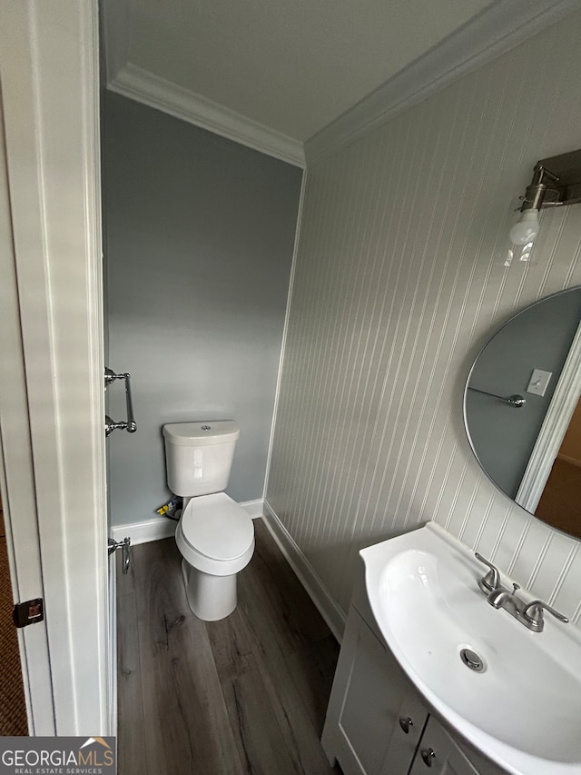 bathroom featuring wood walls, hardwood / wood-style floors, vanity, crown molding, and toilet