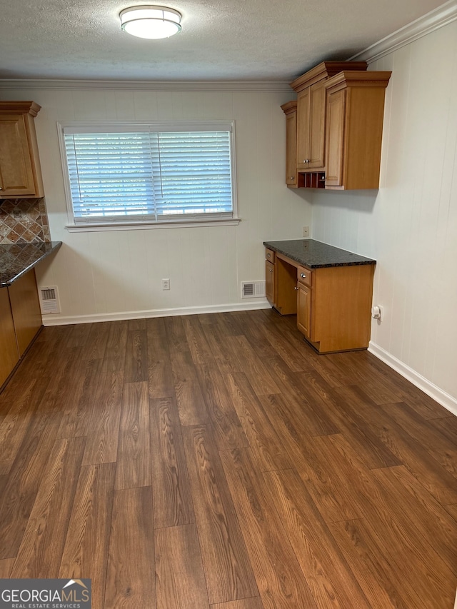 unfurnished dining area with a wealth of natural light, crown molding, built in desk, and dark hardwood / wood-style flooring