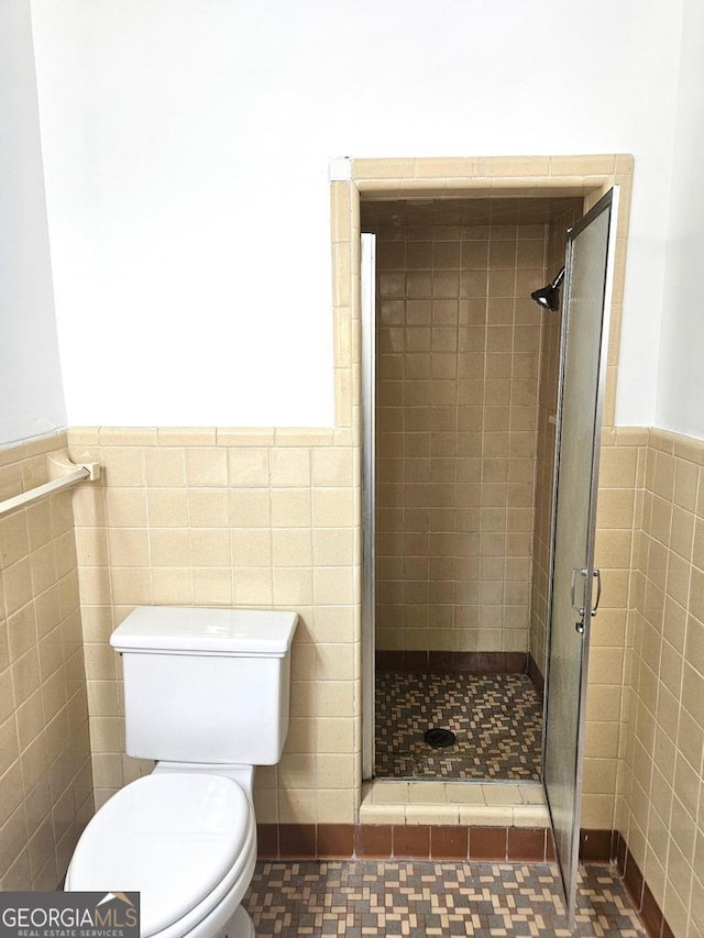 bathroom featuring toilet, tile walls, and walk in shower