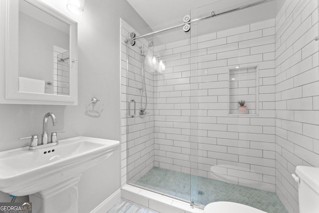 bathroom featuring sink, toilet, and a tile shower