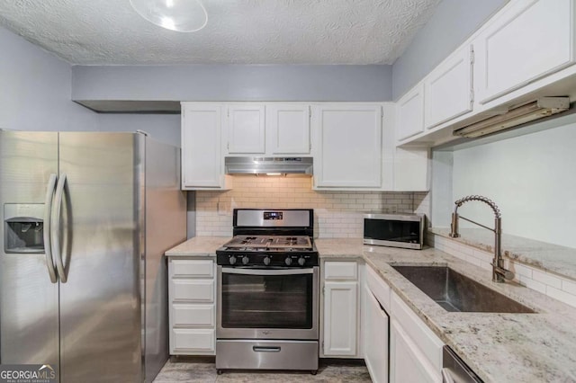 kitchen with white cabinetry, sink, light stone counters, and stainless steel appliances