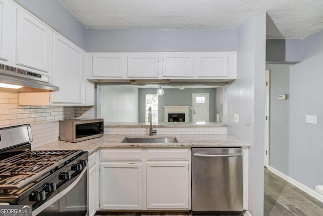 kitchen with stainless steel appliances, a textured ceiling, sink, light hardwood / wood-style floors, and white cabinets