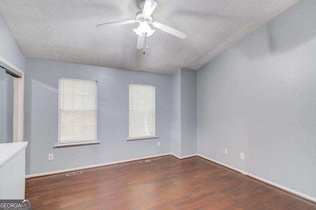 unfurnished room featuring dark wood-type flooring, ceiling fan, and a textured ceiling